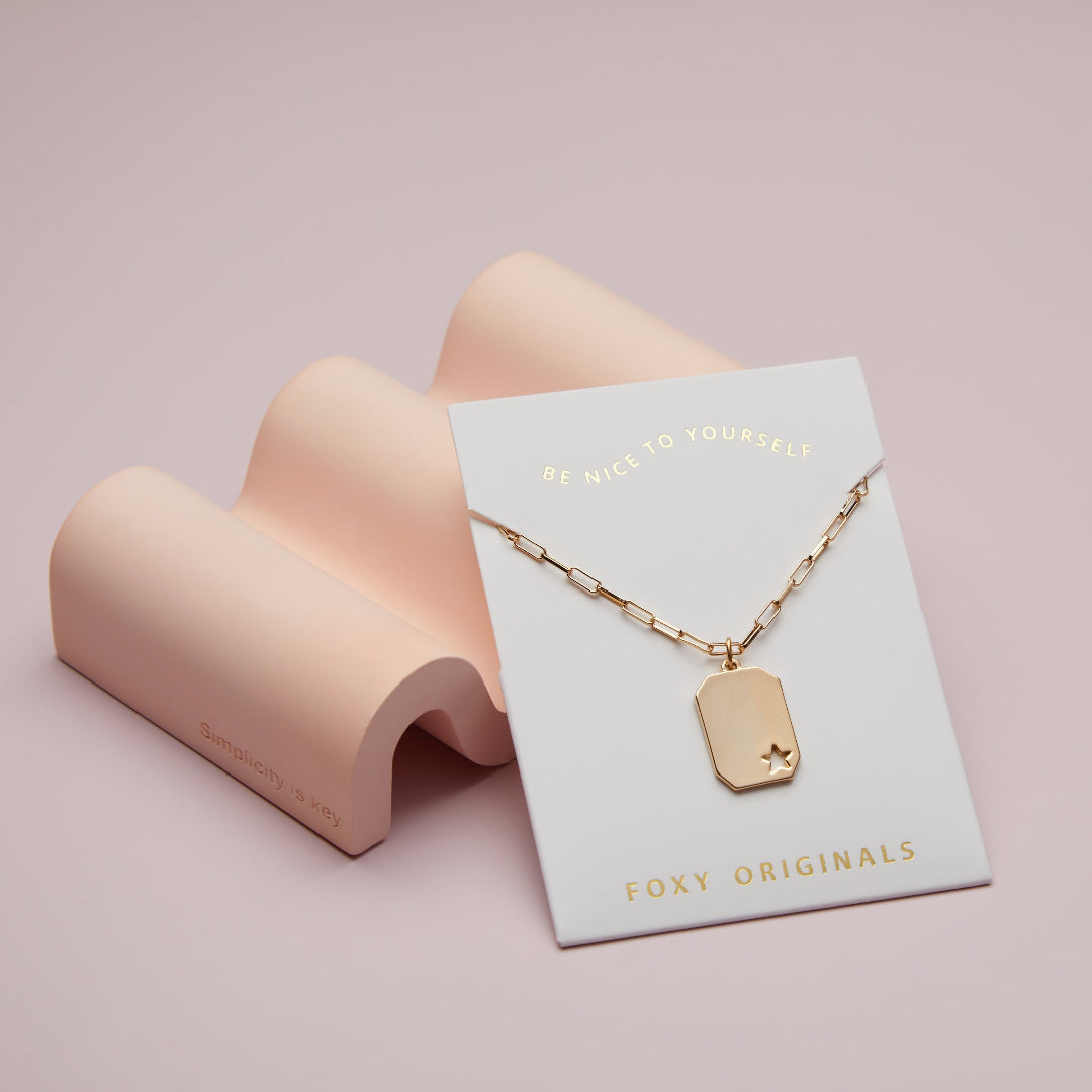 Gold necklace on a 'Foxy Originals' card with a pink stand on a light pink background