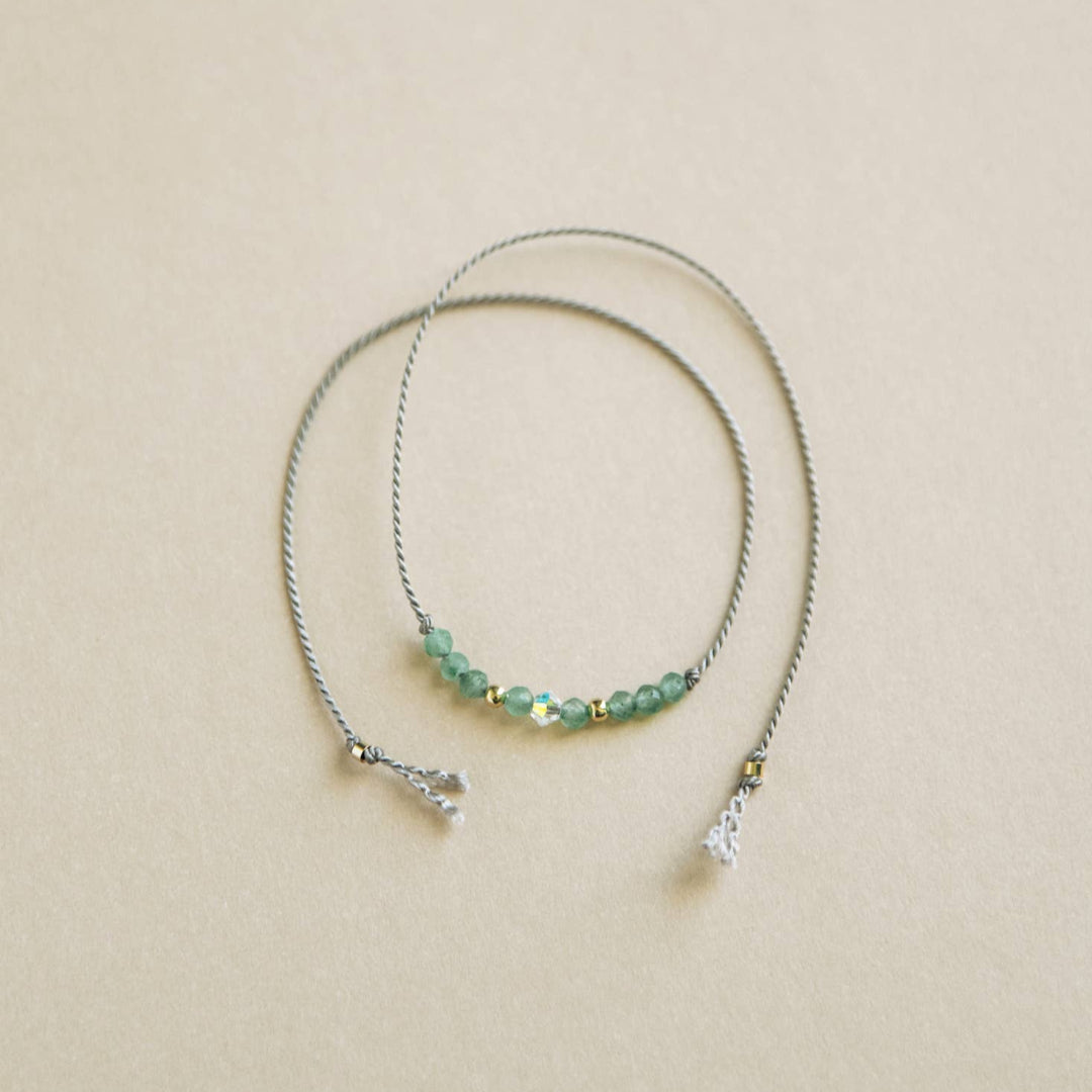 Beaded necklace with green beads on a beige background