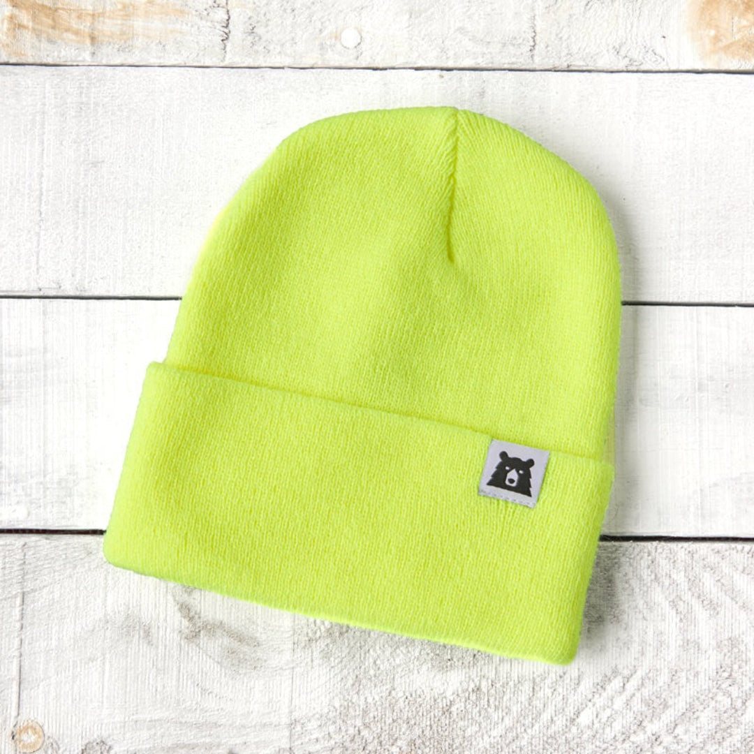 Neon green beanie with a small label on a light wooden surface