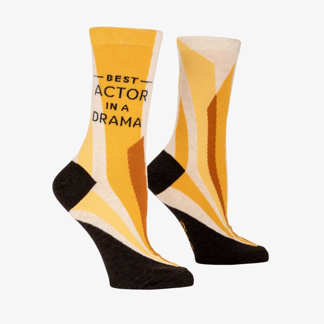 A pair of women's crew socks with a vibrant design of yellow and orange rays emanating from the bottom. Text on one sock reads "BEST ACTOR IN A DRAMA".