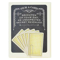 A greeting card with a dark grey background and a decorative white border at the top. The text "PICK A CARD" is at the top, followed by "BRIGHTEN UP YOUR DAY, AN UNEXPECTED SECRET REVEALED." Below the text are five fan-arranged cards with a yellow and white patterned back, held by a paperclip. A second image shows five individual fortune cards, each resembling a playing card with suit symbols and text. The fortunes include messages like "YOUR LUCK IS ABOUT TO CHANGE," "ALL YOUR DREAMS WILL COME TRUE," and "