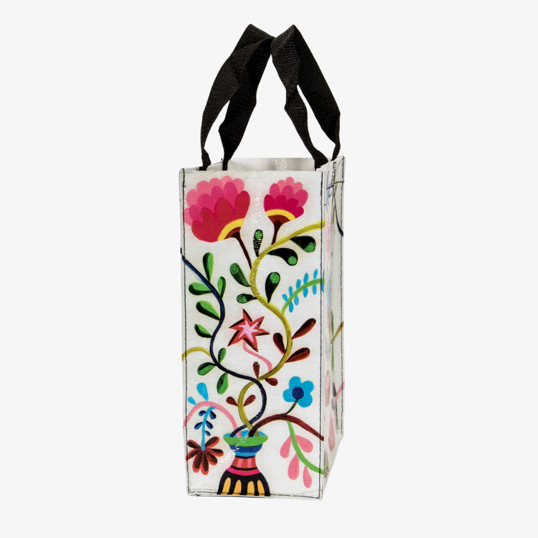 A reusable tote bag with a playful cat design. The bag is white with a black cat standing on its hind legs near a bowl of food. The text "CHOW TIME" is written above the cat, and the bag is decorated with colorful flowers and plants.