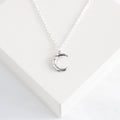 Silver necklace with a crescent moon pendant on a white background