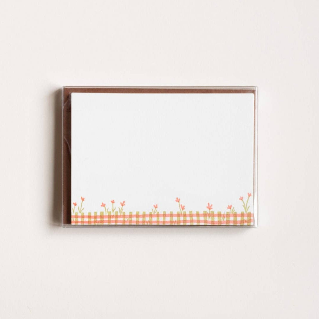Framed artwork with a checkered pattern and floral design on a white wall.