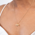Gold necklace with a small pendant on a person wearing a white top.