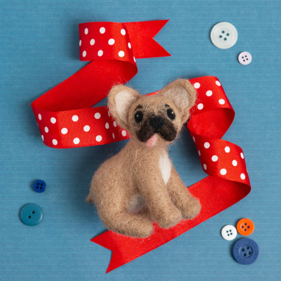 Small brown teddy bear on a red polka dot ribbon with buttons on a blue background