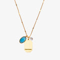 A gold necklace with a turquoise stone pendant. The pendant also has the word "FRIENDSHIP" engraved on it. The necklace is displayed on a blue card with the month "December" and the brand name "Foxy Originals."