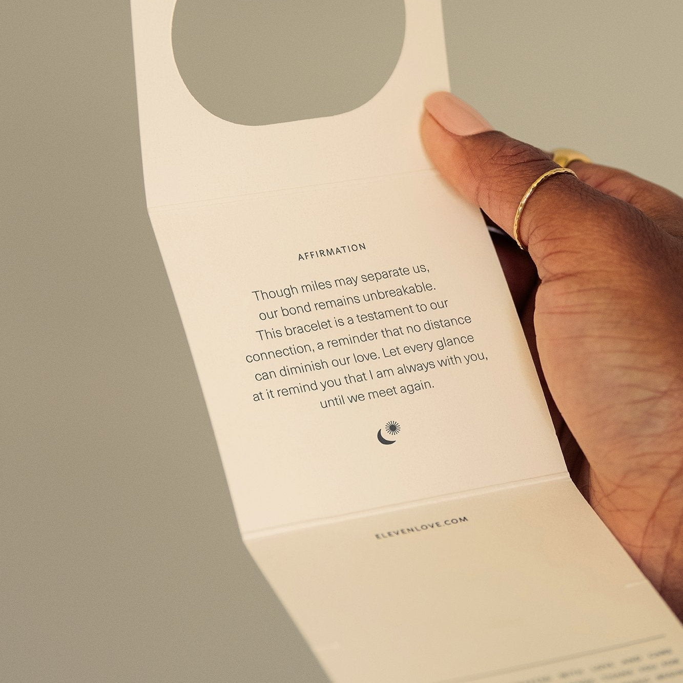 Hand holding a small card with text and a circular cutout on a plain background