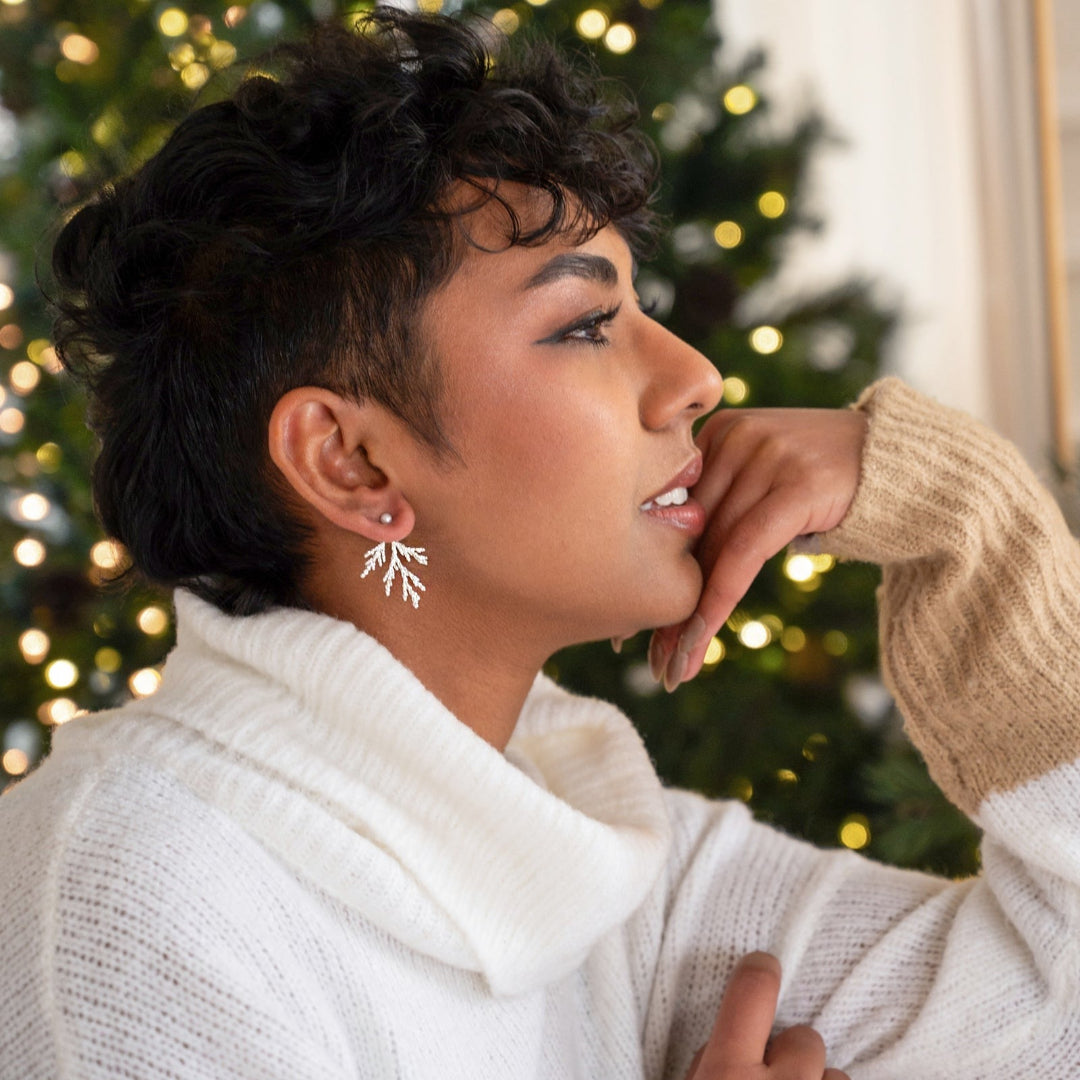 Person wearing a white sweater with a Christmas tree in the background
