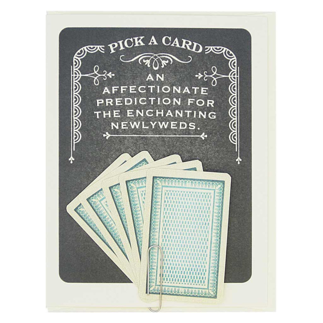 Card with playing cards and text 'Pick a card, an affectionate prediction for the enchanting newlyweds' on a dark background.