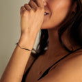 Woman with hand near mouth against a neutral background