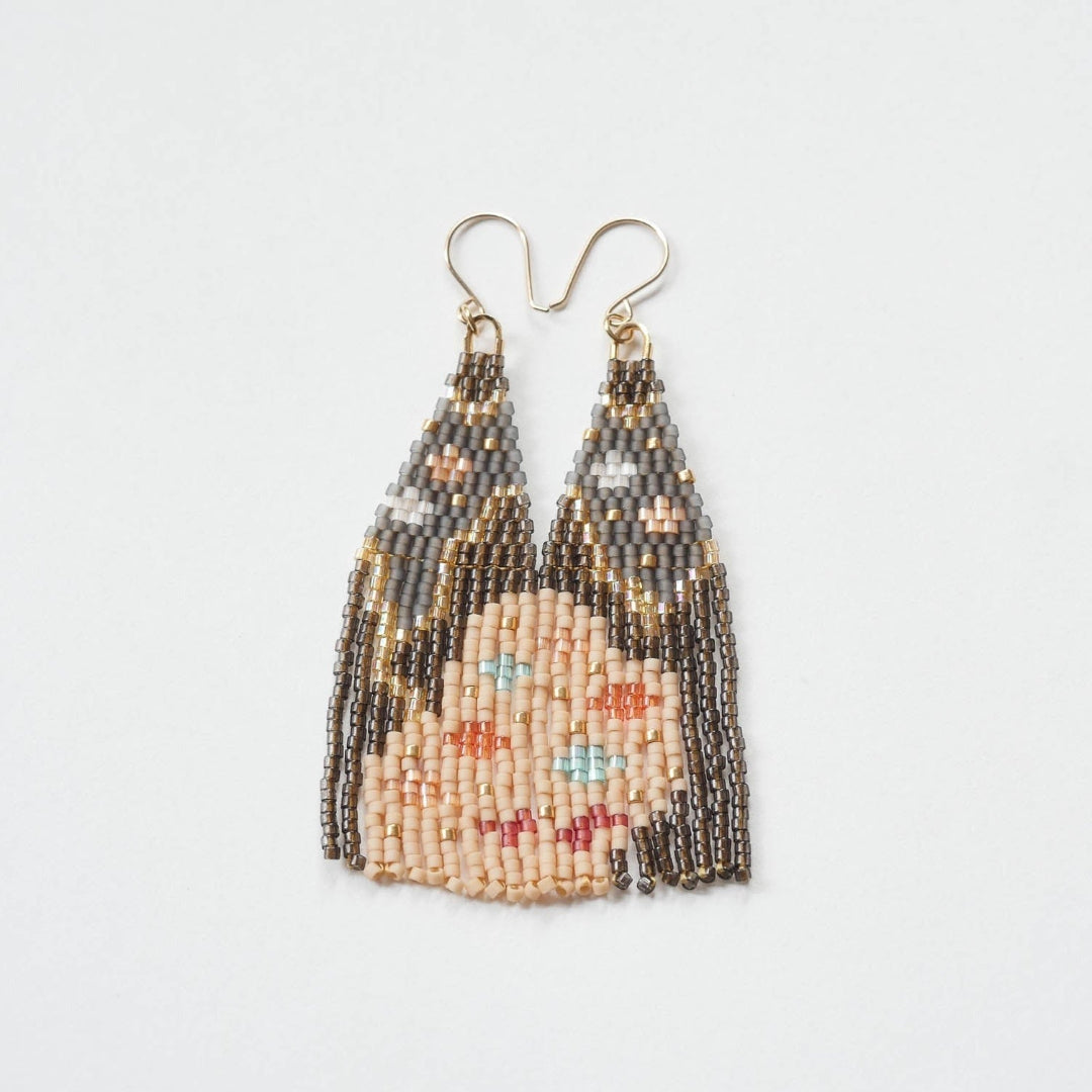 A pair of long, triangular tapestry-style earrings hand-stitched with small Japanese glass beads to depict a stylized face with light peach skin, blue eyes, coral cheeks, and a red mouth, framed by dark brown and grey hair with gold bead accents. They hang from delicate 14 KT gold filled fishhook ear wires.
