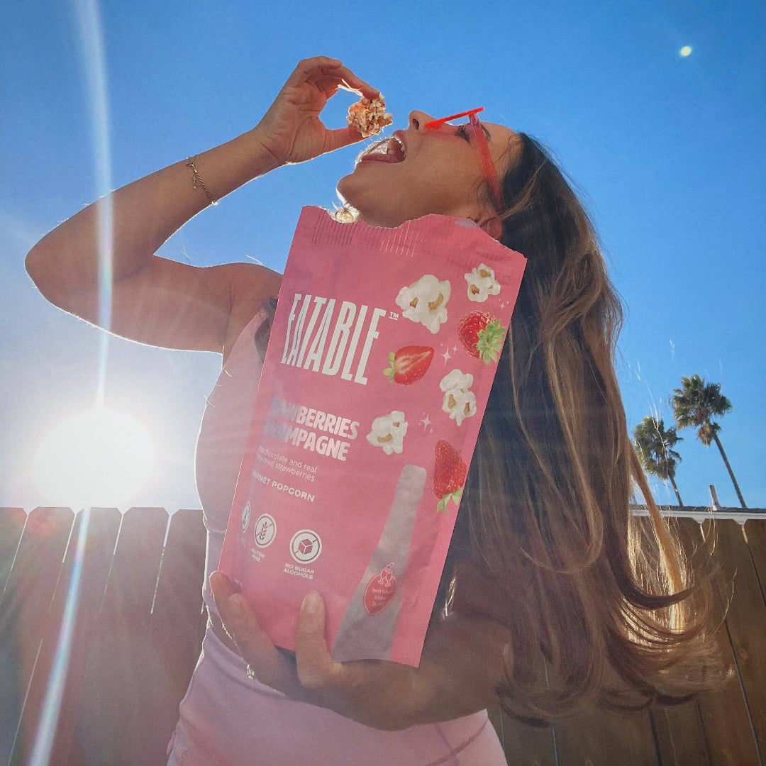 Person holding a pink snack package with a clear blue sky in the background