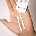 Hand holding a cotton swab with 'everist' packaging against a neutral background