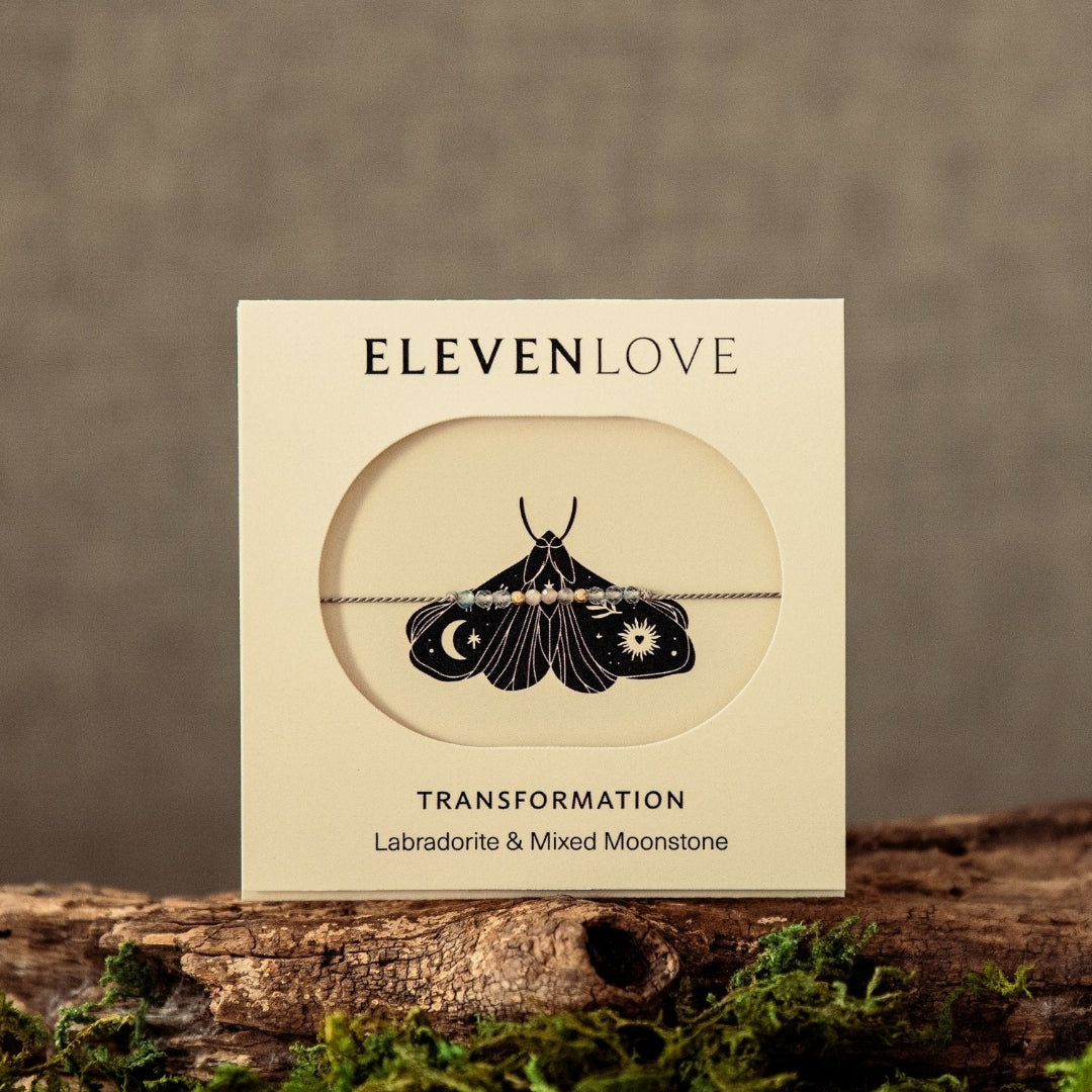 Box of Eleven Love transformation jewelry on a wooden surface with moss