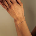 Close-up of a person's arm with a gold bracelet against a neutral background