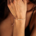 Close-up of a hand wearing a delicate bracelet with a blurred background