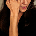 Woman wearing a delicate bracelet on her wrist with a neutral background