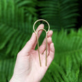 Hand holding brass crescent hair fork 